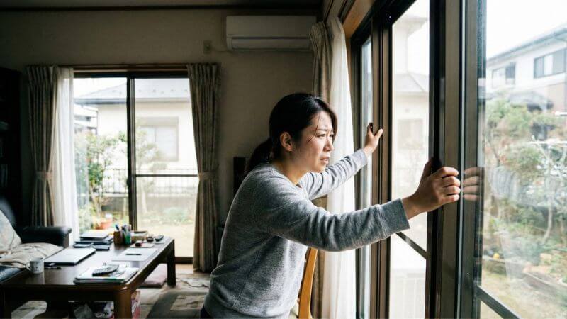 ガス臭を感じて窓を大きく開けて緊急換気を行う女性の安全対応