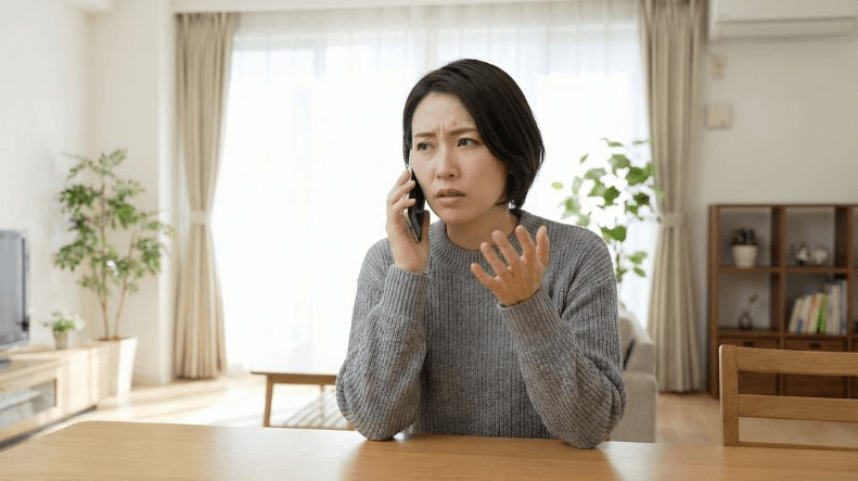 給湯器トラブルについて管理会社に電話で連絡する女性